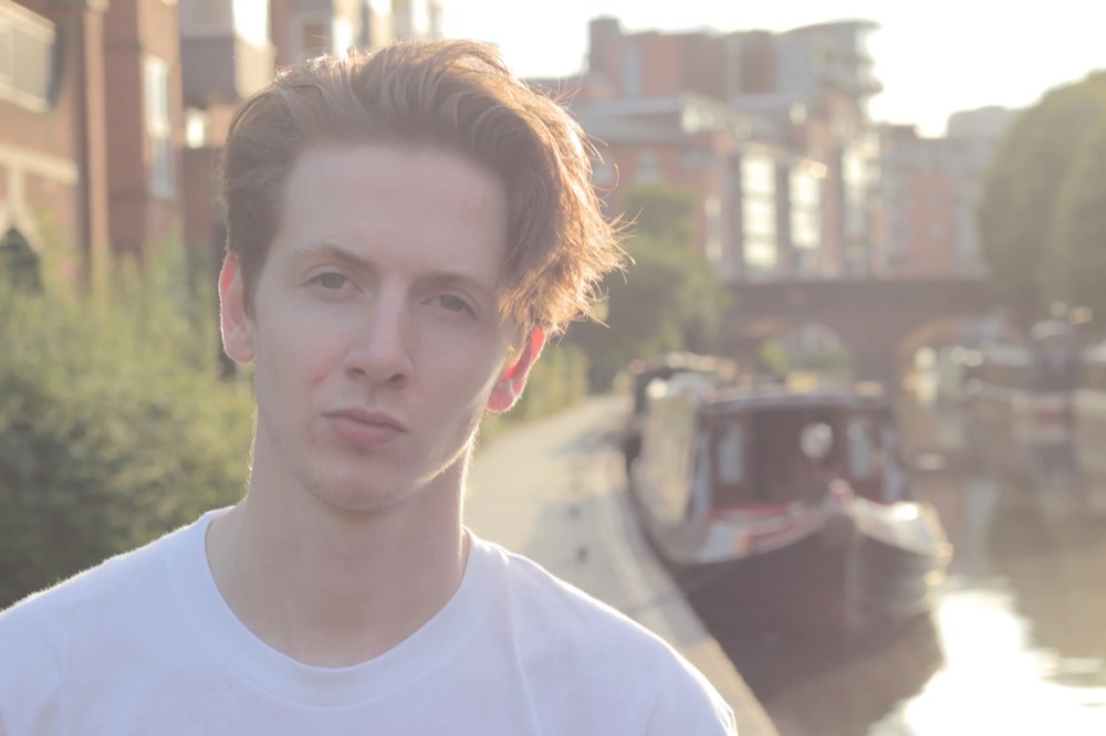 Portrait of a young man beside a canal in golden evening light