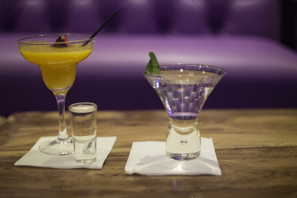 Two cocktails on a low-lit bar table