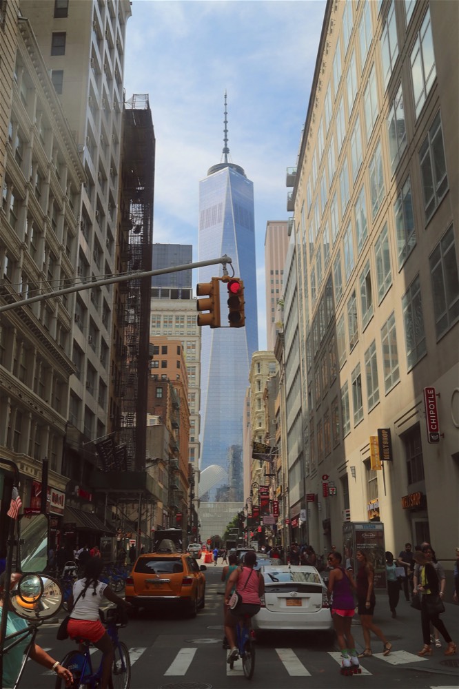 A busy Manhattan street looking up to One World Trade Center